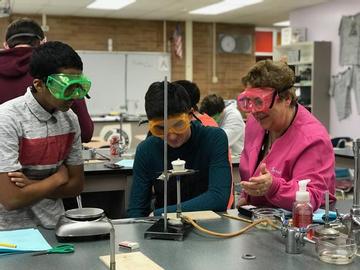 Chemistry teacher working with students in a lab